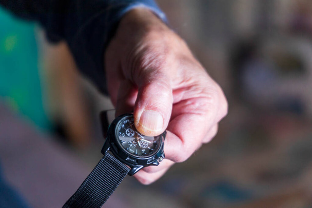 Viejo sosteniendo un reloj de pulsera militar - Foto, imagen