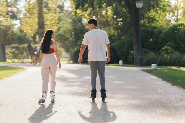 Two young friends skating with inline skates in a park - Foto, imagen