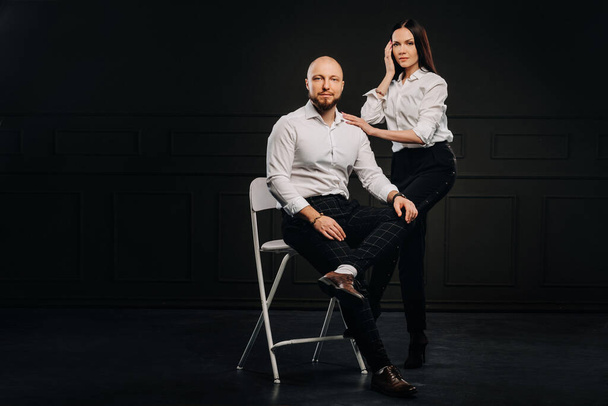 A man and a woman in white shirts on a black background.A couple in love in the studio interior. - Valokuva, kuva