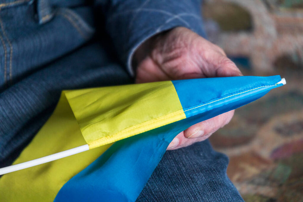 Bir adam elinde Ukrayna 'nın küçük mavi ve sarı bayrağını tutuyor. - Fotoğraf, Görsel