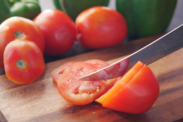 Mano della persona che taglia i pomodori sul tagliere  - Foto, immagini
