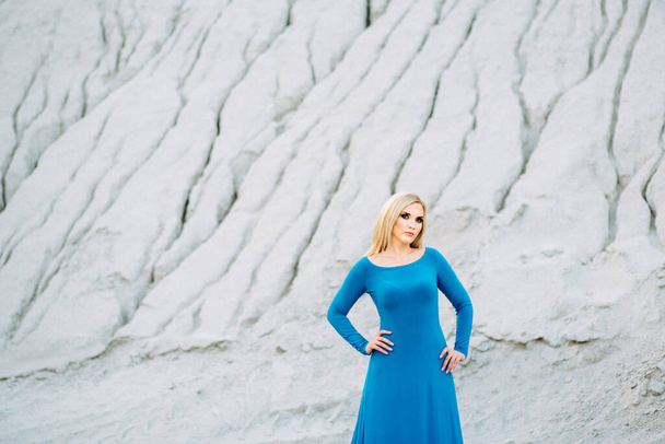 блондинка в блакитній сукні з блакитними очима на гранітному кар'єрі на фоні гравію
 - Фото, зображення
