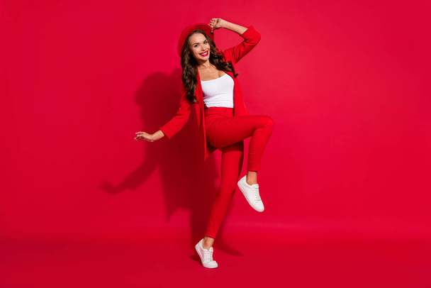 Full body photo of impressed brunette lady dance wear cap suit sneakers isolated on red color background. - 写真・画像