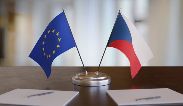 Σημαίες της Τσεχίας και της ΕΕ στο τραπέζι. Διαπραγμάτευση μεταξύ της Ευρωπαϊκής Ένωσης και της Τσεχικής Δημοκρατίας. 3D αποτύπωση. - Φωτογραφία, εικόνα