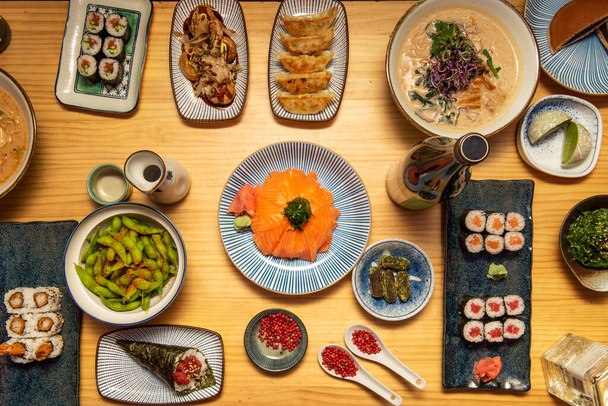 Pratos de comida japonesa com sushi variado, gyozas, bolinhos de massa, polvo takoyaki, temaki atum vermelho, edamame em vagens, hosomaki, pimenta vermelha, trufas matcha, nori algas e algas marinhas wakame - Foto, Imagem