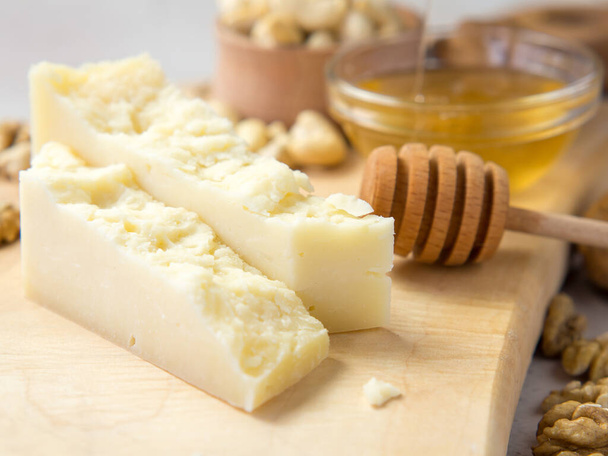 rodajas de queso duro en una tabla de madera con nueces y miel la mejor combinación - Foto, Imagen
