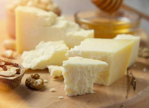 τυρί αγροκτήματος σερβίρεται με μέλι και ξηρούς καρπούς σε ελαφρύ φόντο υφή. Αντιγραφή χώρου - Φωτογραφία, εικόνα