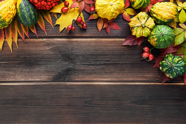 Herbstlicher Hintergrund mit dekorativen Kürbissen und bunten Blättern auf einem dunklen Holztisch. Happy Thanksgiving-Konzept. - Foto, Bild