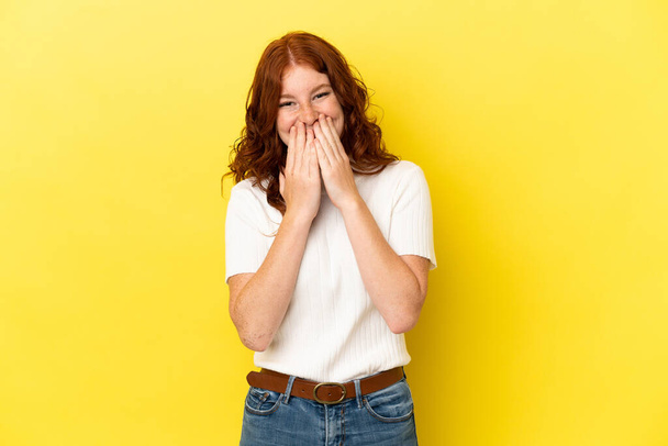 nastoletnia rudawa kobieta odizolowana na żółtym tle szczęśliwa i uśmiechnięta pokrywająca usta dłońmi - Zdjęcie, obraz