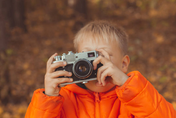 Niño con cámara retro tomando fotos al aire libre en la naturaleza de otoño. Concepto de ocio y fotógrafos - Foto, Imagen