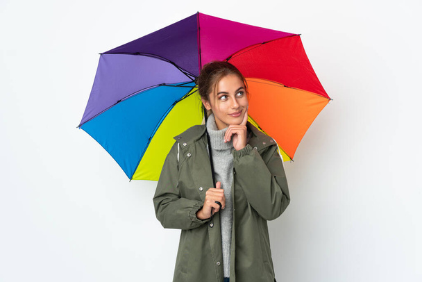 Nuori nainen tilalla sateenvarjo eristetty valkoisella taustalla ajattelu ajatus etsiessään - Valokuva, kuva