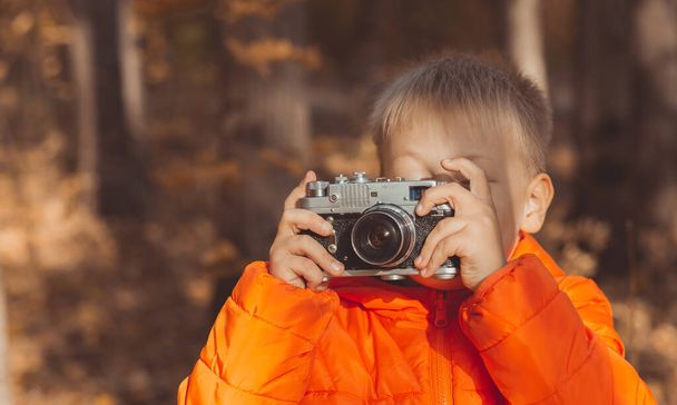 Boy with retro camera taking pictures outdoor in autumn nature. Leisure and photographers concept - Φωτογραφία, εικόνα