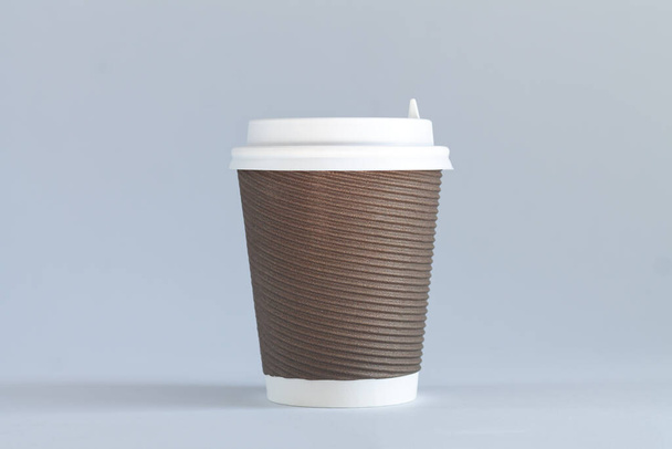 Jeden brązowy jednorazowy kubek do kawy z białymi wieczkami z bliska. Pojęcie "na wynos" - Zdjęcie, obraz