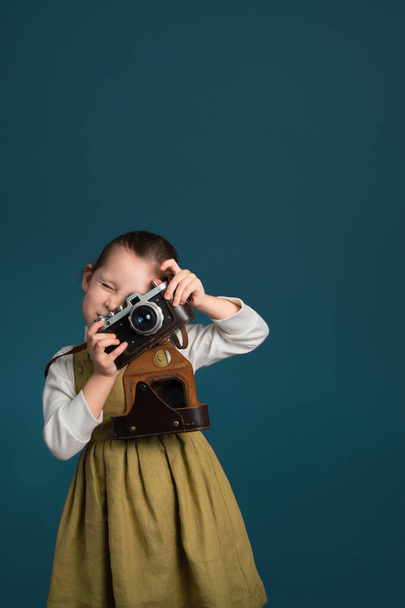 Beautiful little girl photographer with retro camera. Studio vertical portrait with copy space. - Foto, imagen