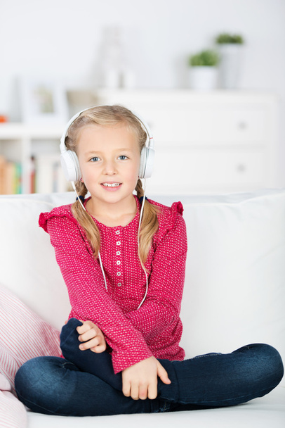 Girl with headphones sitting on sofa - Zdjęcie, obraz