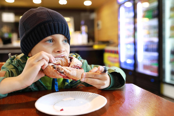 Boy eating braided bun with jam in restaurant - Zdjęcie, obraz