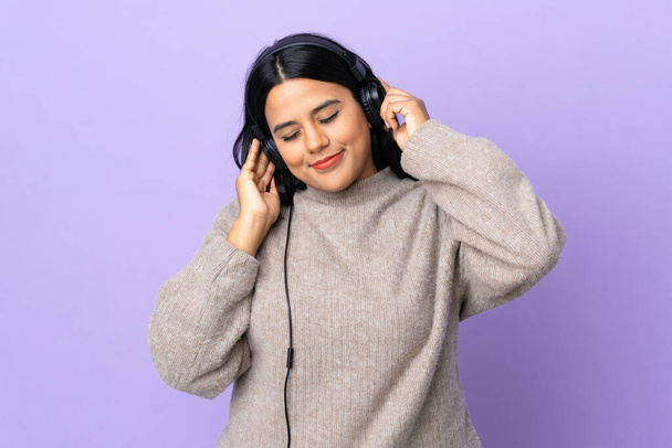 Mujer latina joven aislada sobre fondo púrpura escuchando música y cantando
 - Foto, imagen