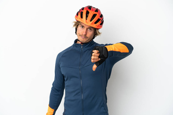 Young blonde cyclist man isolated on white background showing thumb down with negative expression - Valokuva, kuva