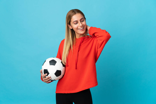Young football player woman isolated on blue background laughing - 写真・画像
