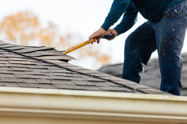 roofer removing roof shingles with roof shingle remover - Photo, Image