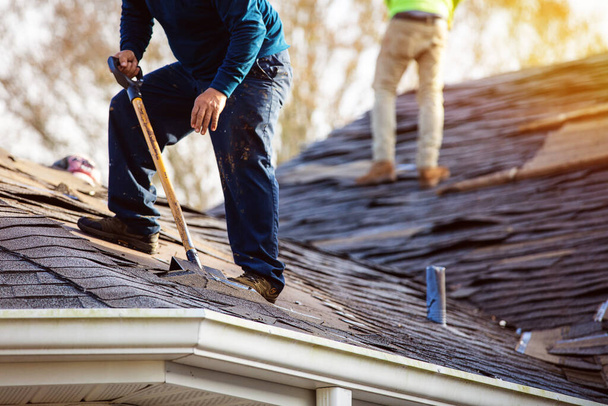roofer removing roof shingles with roof shingle remover - 写真・画像