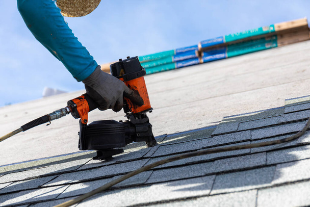 roofer installing roof shingles with pneumatic roofing nailer. - Zdjęcie, obraz