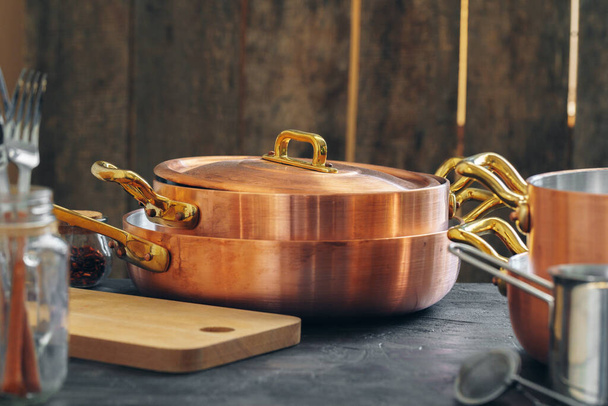 Copper cookware with wooden kitchen utensils close up - Foto, imagen