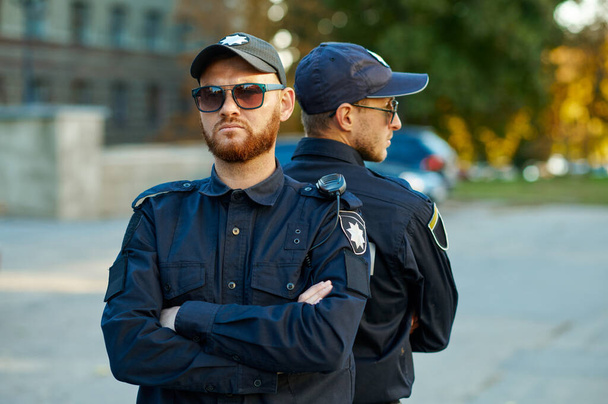 Dos policías masculinos parados espalda con espalda - Foto, imagen
