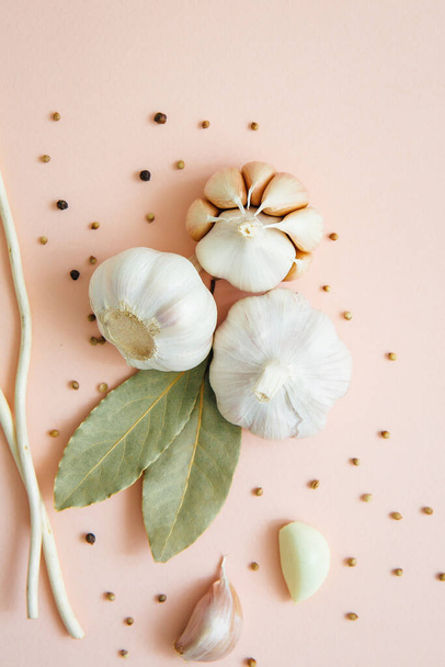 Garlic on pink background with spices, peppercorns and bay leaves. Spices and condiments. Food background. Vegetarianism. Selective focus. - Foto, Bild