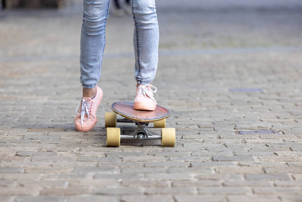 スニーカーで若い女性の足の切り取られたショットは、公園のスケートボードで新しいトリックを練習します。スポーツと都市生活のコンセプト - 写真・画像