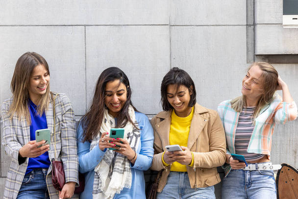 Multiraciale groep tieners hebben plezier spelen gelukkig met smartphones. Gebruik door millennials van mobiele telefoons en sociale toepassingen.  - Foto, afbeelding