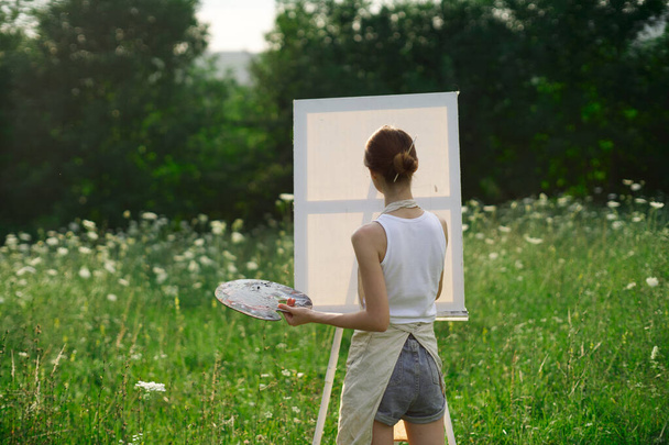 woman artist outdoors with palette of paints paints a picture - Photo, image