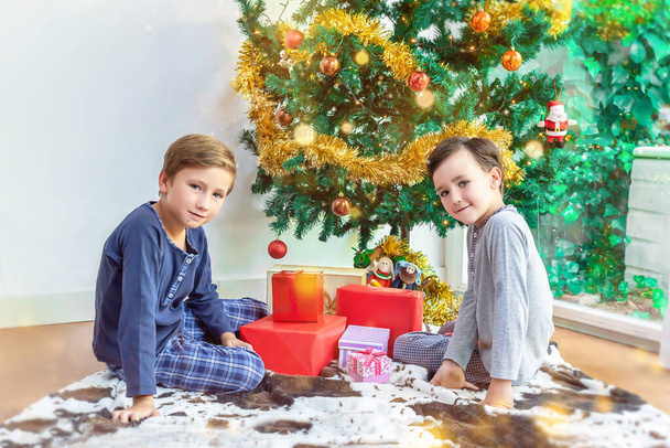 Children by the Christmas tree ready to open their presents - Фото, изображение