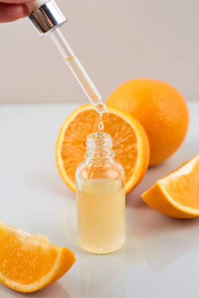 Pipette with orange essential oil over bottle and oranges. Natural medicine concept. Aromatherapy - Photo, image