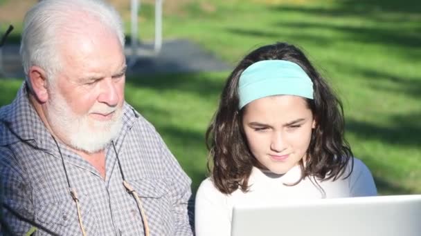 Starszy mężczyzna wyjaśnia wnuczce, jak używać laptopa. - Materiał filmowy, wideo