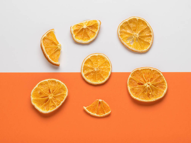 Розкидані шматочки сушеного апельсина на білому і помаранчевому тлі. Смачні та здорові цукати
. - Фото, зображення