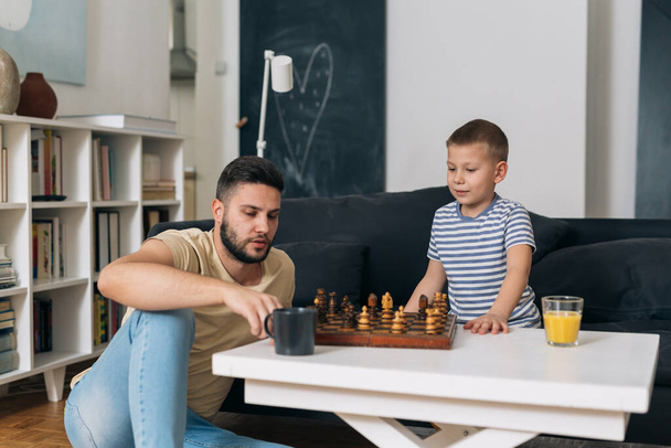 father and son playing chess at home - Foto, afbeelding