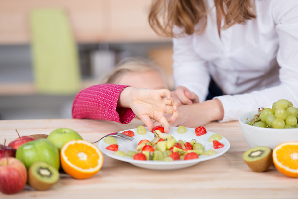 Girl picking fruit salad from plate - Photo, Image