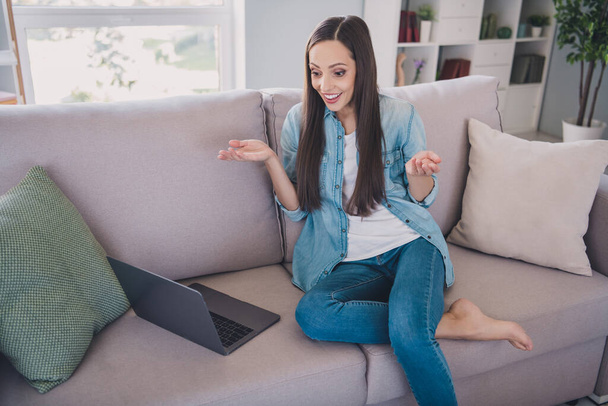Retrato de mulher de cabelos longos alegre atraente sentado no divã usando laptop chamando falar se divertindo em casa dentro de casa - Foto, Imagem
