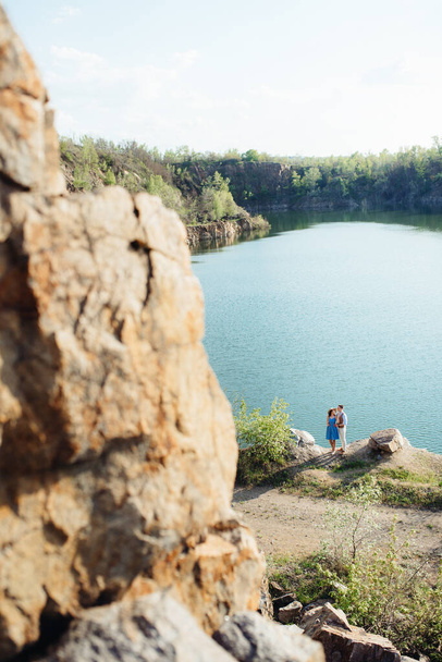 Młoda para, chłopak i dziewczyna spacerują koło górskiego jeziora otoczeni granitowymi skałami. - Zdjęcie, obraz