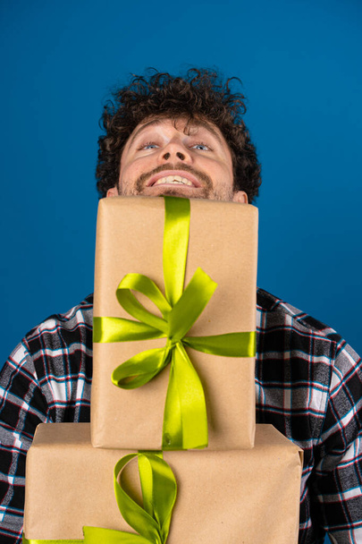 Κοντινό πλάνο ενός ευτυχισμένου άντρα με ένα χαμόγελο στο πρόσωπό του με δώρα στα χέρια του - Φωτογραφία, εικόνα