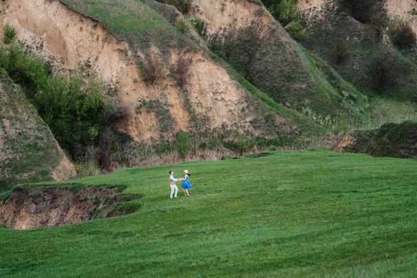 young couple a guy and a girl are walking in the green mountain hills - Foto, imagen