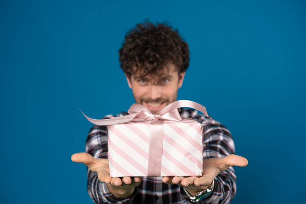 focusing on a small box with a gift in the hands of a smiling guy - Photo, Image