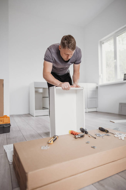 Carpenter assembling furniture service. Portrait of worker assembling kitchen drawer with tools. Full length - Valokuva, kuva