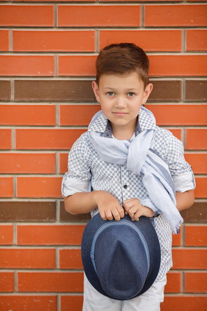 Stylish boy in Hat posing on a brick wall - Fotó, kép