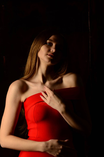 Una hermosa joven con un vestido rojo en el estudio. Joyas de lujo, collares y anillos, maquillaje brillante, labios rojos, manicura. Glamorosa dama de lujo. - Foto, Imagen