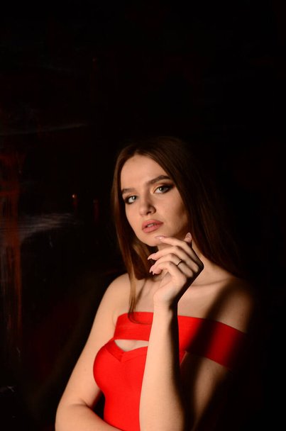 A beautiful young girl in a red dress in the studio. Luxury jewelry, necklaces, and rings, bright makeup, red lips, manicure. Glamorous luxury lady. - Φωτογραφία, εικόνα