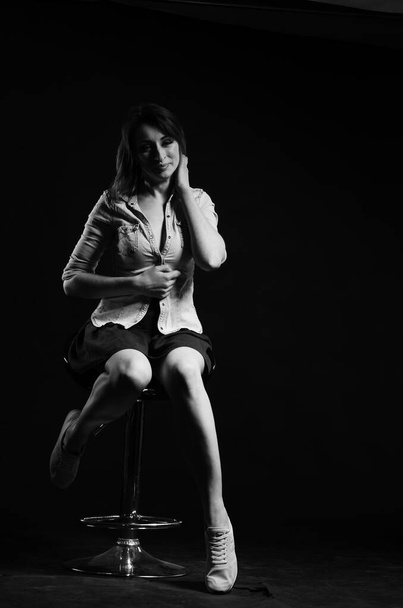 Stüdyoda siyah arka planda poz veren güzel genç bir kadın, moda tarzı, siyah beyaz fotoğraf. - Fotoğraf, Görsel
