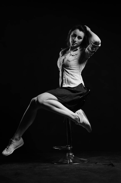 Stüdyoda siyah arka planda poz veren güzel genç bir kadın, moda tarzı, siyah beyaz fotoğraf. - Fotoğraf, Görsel