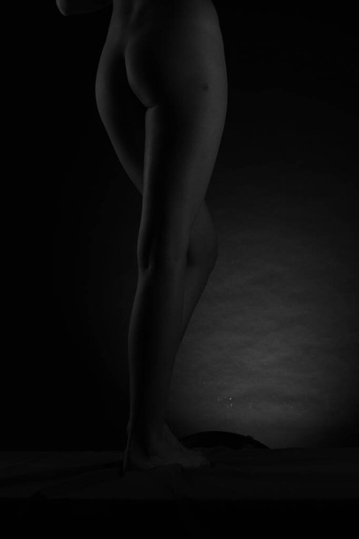 Fekete-fehér Gyönyörű női test. Divatművészeti stúdió portré egy elegáns meztelen hölgyről, rajta árnyékkal. Fekete alapon izolált női gyomor. Erotikus póz alacsony kulcs lövés - Fotó, kép